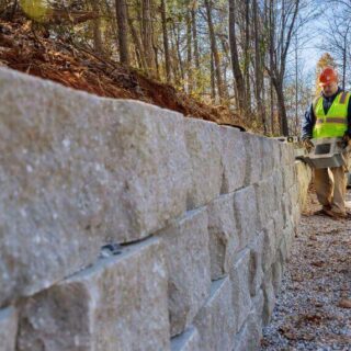 عامل بناء يقوم ببناء جدار استنادي حول المنزل لمنع انهيار التربة واقترابها من المنزل