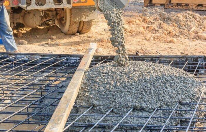 خرسانة يتم انزالها من سيارة الصب الى موقع البناء فوق شبكة من حديد التسليح