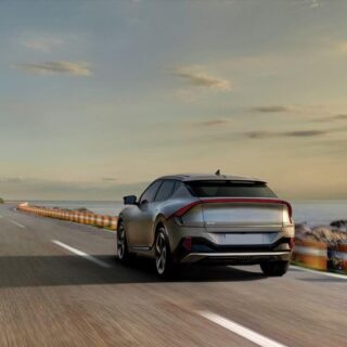 سيارة كهربائية رمادية اللون تسير بسرعة على الكورنيش جانب البحر