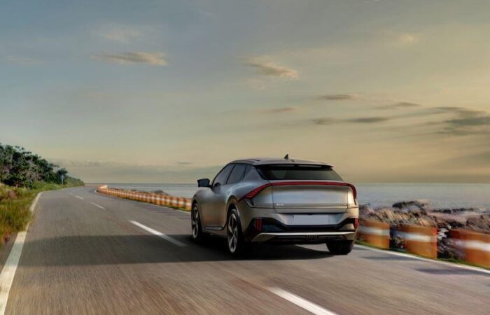 سيارة كهربائية رمادية اللون تسير بسرعة على الكورنيش جانب البحر