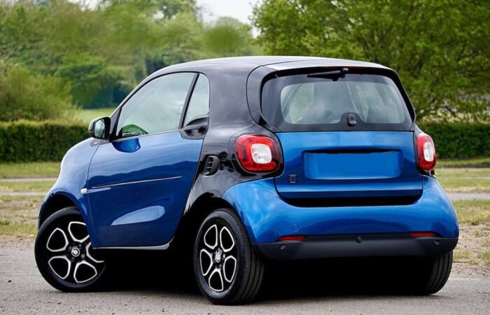 سيارة كهربائية صغيرة زرقاء اللون تقف في باحة امام حديقة خضراء