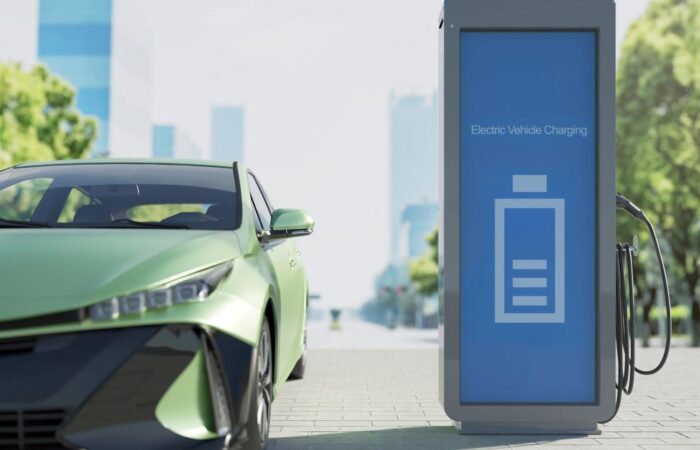 سيارة كهربائية خضراء اللون تقف بجانب محطة لشحن السيارات الكهربائية