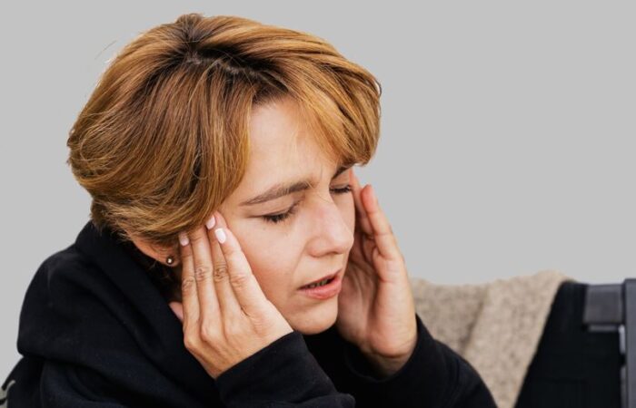 فتاة ترتدي كنزة سوداء تضع يديها على رأسها بسبب معاناتها من الصداع النصفي