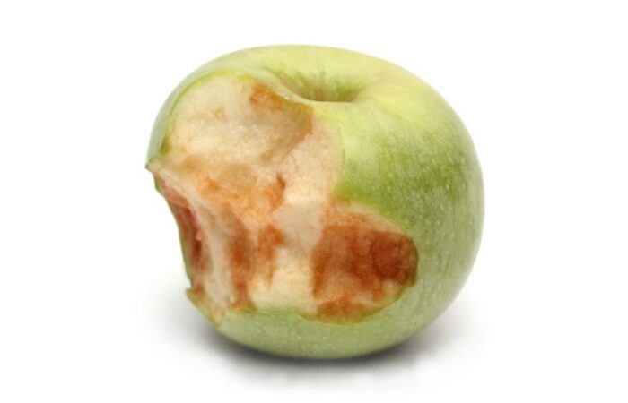 تفاحة خضراء مأكول نصفها وقد اصبح النصف المأكول بني اللون