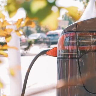 خلفية سيارة كهربائية رصاصية اللون ويظهر كبل الشحن الكهربائي وهو موصول بها من الجهة اليسرى