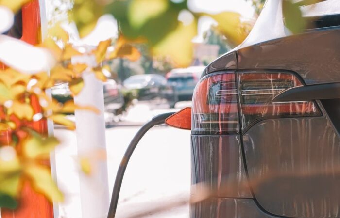 خلفية سيارة كهربائية رصاصية اللون ويظهر كبل الشحن الكهربائي وهو موصول بها من الجهة اليسرى