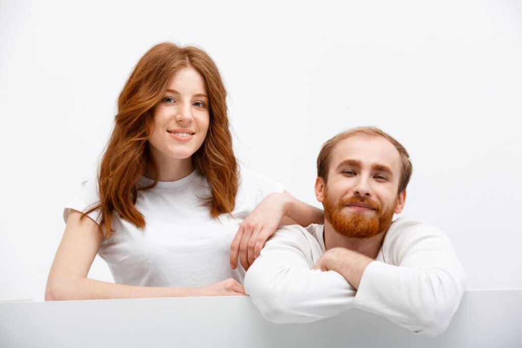 رجل بالغ ذو شعر خمري اللون مع زوجته التي تملك أيضا شعراً خمري اللون وهي تضع يدها على كتف زوجها