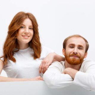 رجل بالغ ذو شعر خمري اللون مع زوجته التي تملك أيضا شعراً خمري اللون وهي تضع يدها على كتف زوجها