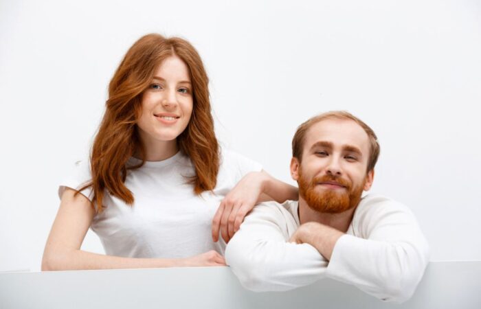 رجل بالغ ذو شعر خمري اللون مع زوجته التي تملك أيضا شعراً خمري اللون وهي تضع يدها على كتف زوجها