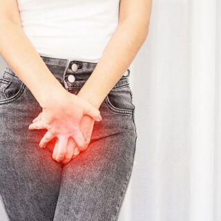 فتاة بالغة تقوم بوضع يديها على بنطالها فوق المنطقة الحساسة بسبب معاناتها من التهابات المهبل