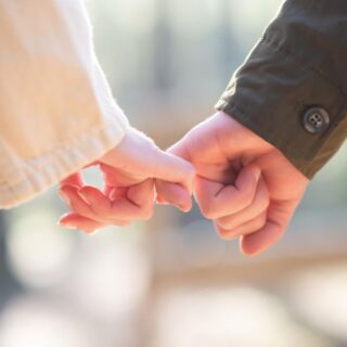 شاب وفتاة يشبكون الأصبع الصغير ليديهم ويسيرون مع بعضهم البعض