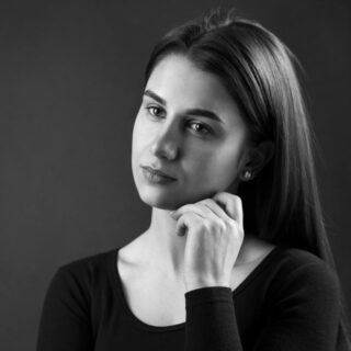 امرأة بالغة ذات شعر أملس ناعم تلبس كنزة سوداء تنظر بتأمل للجهة المقابلة ويبدو عليها علامات الفراغ العاطفي
