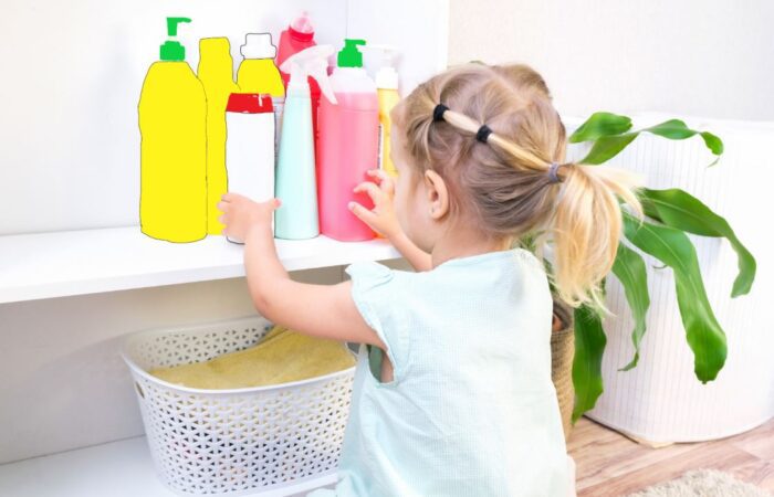 فتاة صغيرة شعرها أشقر تقوم بالتفتيش في علب المنظفات المنزلية الموجودة على رف في المنزل بالقرب من نبتة منزلية