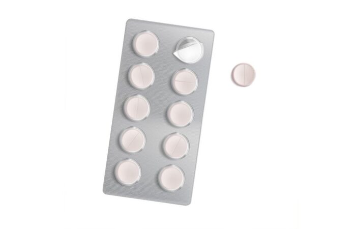 ظرف أقراص دواء الباراسيتامول لونه فضي مع حبة بيضاء اللون جانبه على خلفية بيضاء