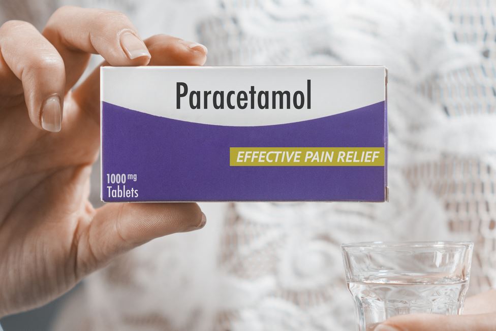 علبة دواء الباراسيتامول لونها بنفسجي وأبيض مكتوب عليها اسم الدواء باللغة الإنكليزية و تمسك بهذه العلبة امرأة