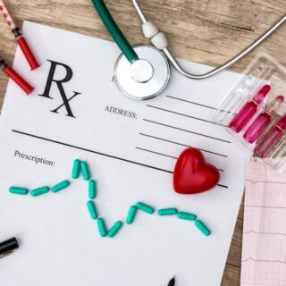 سماعات الطبيب وعينات من الدم و ورقة تخطيط للقلب بالإضافة لقلب أحمر و ورقة بيضاء موضوعين على طاولة لونها بني فاتح