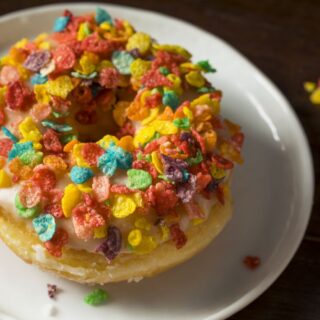 قطعة من الكيك في صحن أبيض وتوجد على قطعة الكيك قطع تزيين صغيرة ملونة بألوان مختلفة