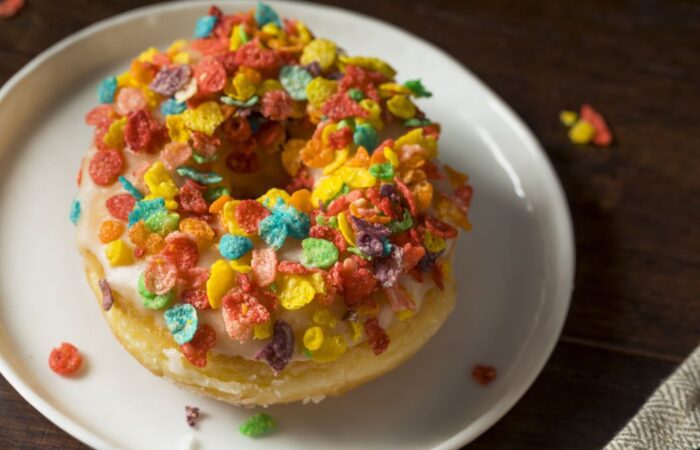 قطعة من الكيك في صحن أبيض وتوجد على قطعة الكيك قطع تزيين صغيرة ملونة بألوان مختلفة