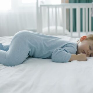 طفل صغير أشقر يلبس ثياب النوم وبنام على بطنه