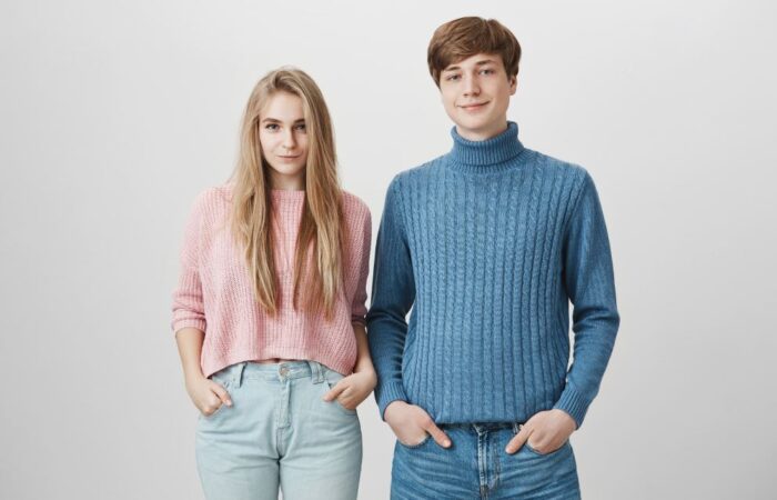 شاب يلبس كنزة زرقاء وفتاة تلبس كنزة زهرية يقفان بجانب بعضهما البعض