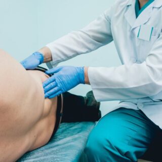 طبيب يقوم بفحص خاصرة مريض مستلقي على السرير في العيادة الطبيبة