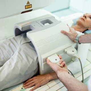طبيب يقوم بوضع جهاز التصوير بالأشعة على بطن امرأة بالغة من اجل تشخيص المرض