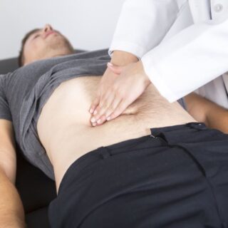 طبيب يقوم بالضغط على بطن مريض مستلقي على السرير