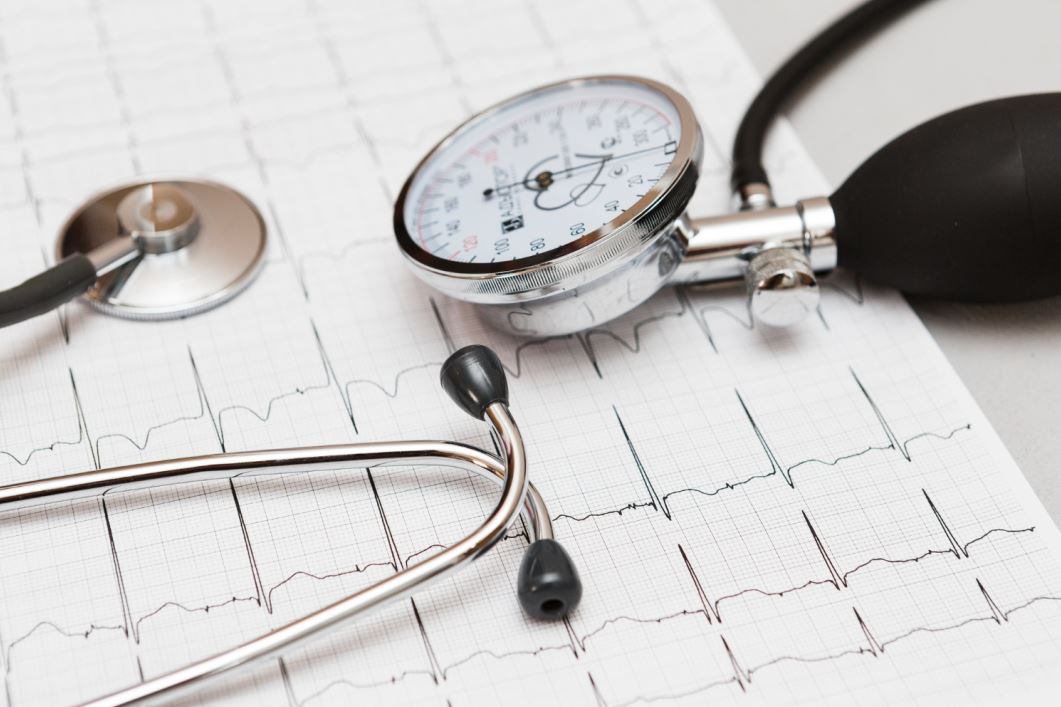 جهاز قياس ضغط الدم التقليدي وسماعات الطبيب على ورقة رسم بياني لتخطيط القلب
