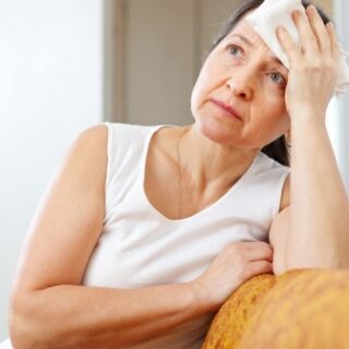 امرأة اربعينية تجلس واضعة يدها على جبينها وتظهر مرتبكة