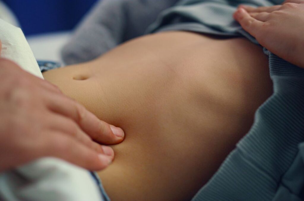 طبيب يضع يده على بطن ولد صغير من أجل فحص المنطقة البطنية لديه