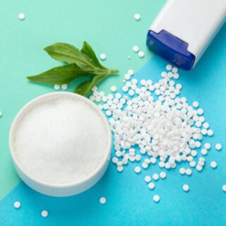 حبوب بيضاء صغيرة تخرج من علبة بيضاء اللون وبجانبهم زبدية بها مادة بيضاء وورقة نعناع أخضر