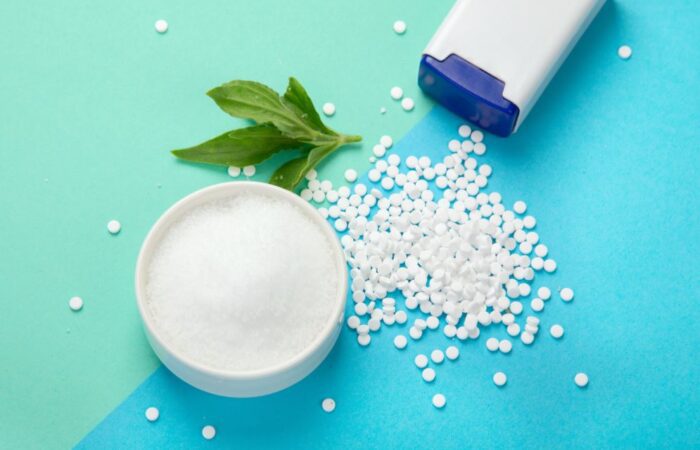 حبوب بيضاء صغيرة تخرج من علبة بيضاء اللون وبجانبهم زبدية بها مادة بيضاء وورقة نعناع أخضر