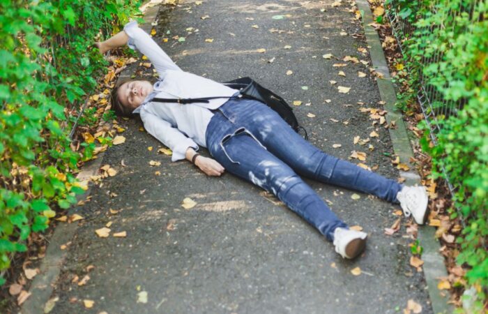 فتاة مغمضة العينين ممدة على الأرض وبجانبها حقيبة كتف ونظارات شمسية