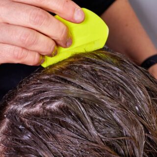 ام تقوم بتمشيط شعر ابنتها بمشط أصفر اللون