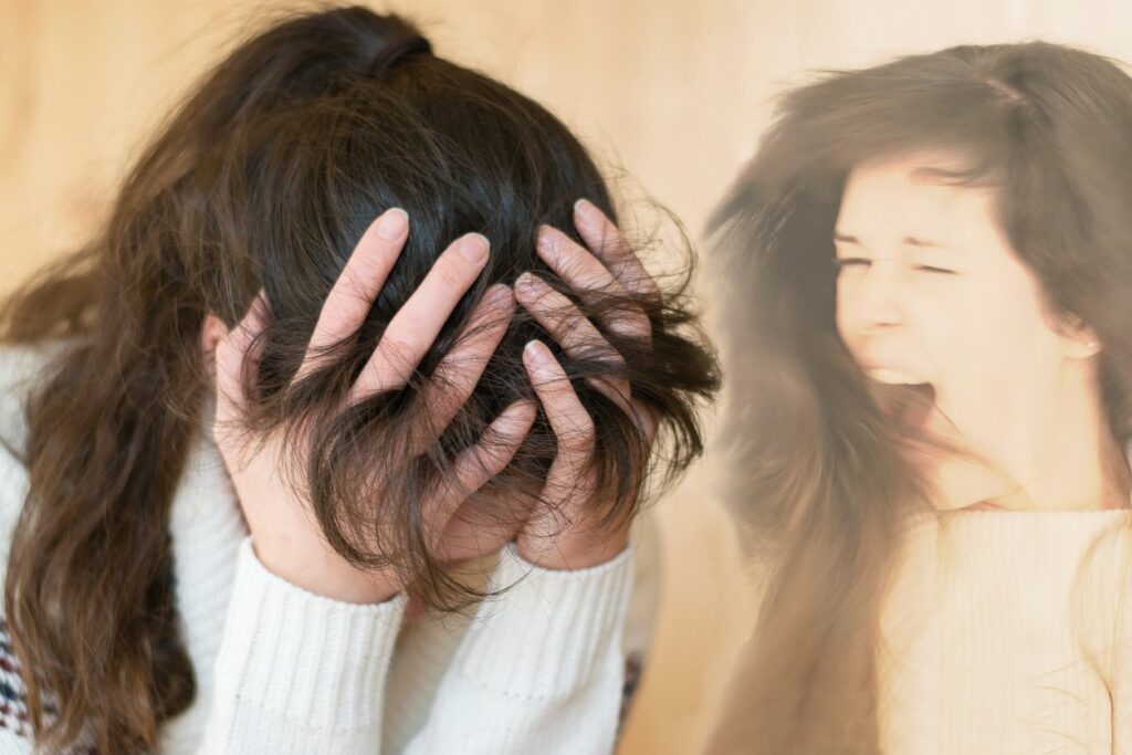امرأة بالغة تلبس كنزة بيضاء تقوم بوضع يديها على رأسها وهي خافضة الرأس وبجانبها صورة مكررة لها وهي تصرخ