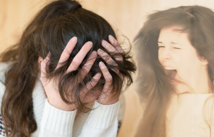 امرأة بالغة تلبس كنزة بيضاء تقوم بوضع يديها على رأسها وهي خافضة الرأس وبجانبها صورة مكررة لها وهي تصرخ