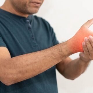 رجل بالغ يرتدي كنزة رمادية ويقوم بمسك معصم يده اليمنى