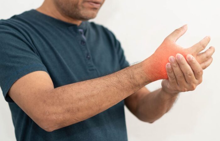 رجل بالغ يرتدي كنزة رمادية ويقوم بمسك معصم يده اليمنى