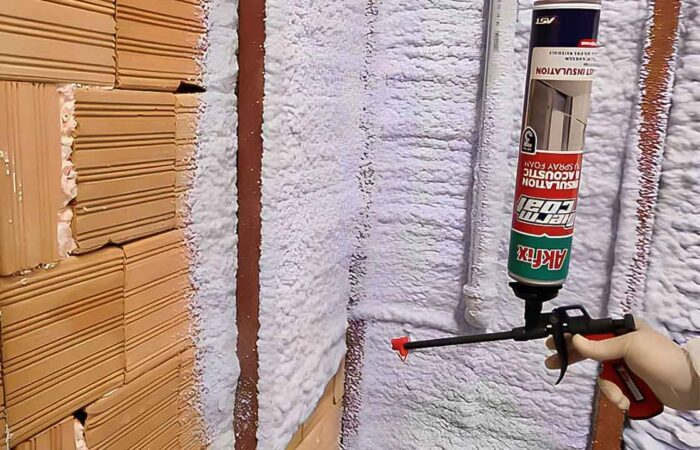 شخص يقوم برش مادة البولي يوريثان الرغوية البيضاء على حائط قرميد بنيّ
