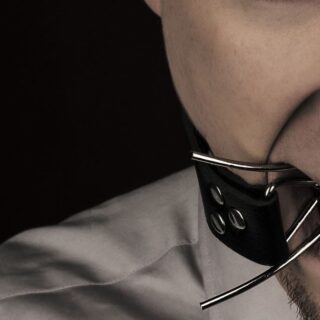 شخص يضع قطعة معدنية في فمه ويتصل بها قشاط أسود اللون