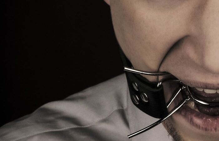 شخص يضع قطعة معدنية في فمه ويتصل بها قشاط أسود اللون