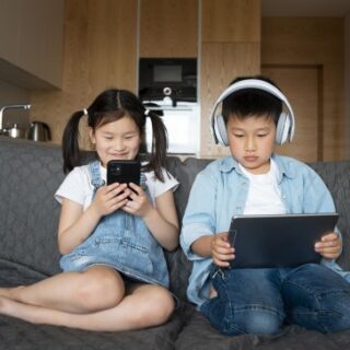 صبي وفتاة يجلسون على الأريكة ويستخدمون أجهزتهم الالكترونية