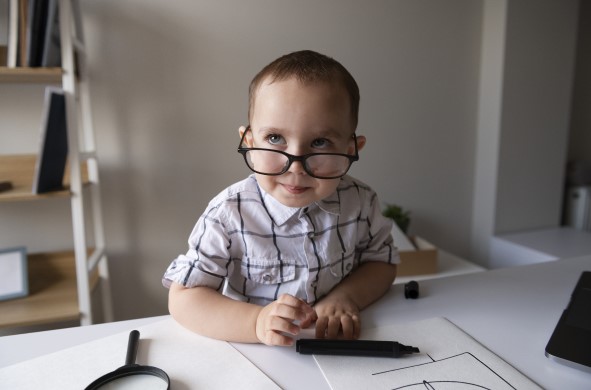 طفل مبتسم يرتدي نظارة ويمسك بيده قلم