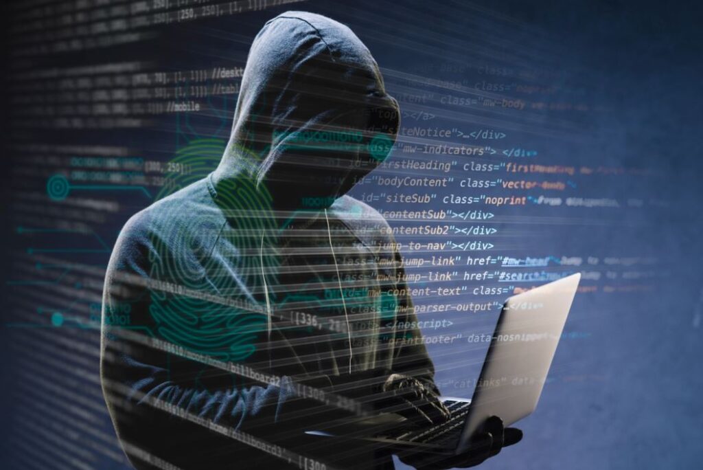 شخص يرتدي كنزة ذات قبعة يضعها على رأسه ويحمل بين يديه جهاز لابتوب