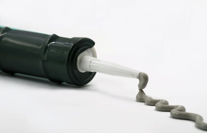 انبوب من البلاستك يخرج منه معجون لامع رمادي اللون