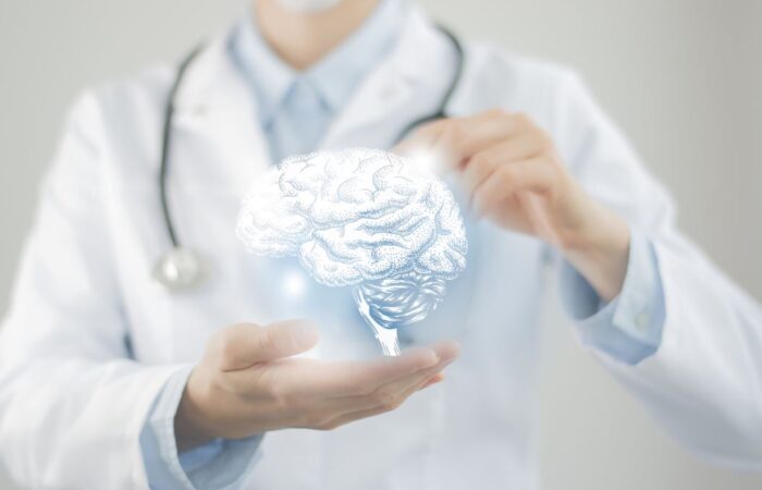 طبيب يرتدي ملابس بيضاء وبين يديه توجد رسمة للدماغ البشري