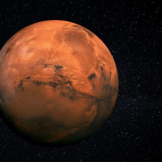 كوكب المريخ على شكل كرة برتقالية اللون تطفو وسط ظلام تتخلله بقع بيضاء لامعة