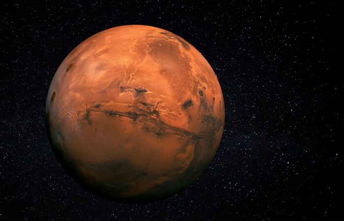 كوكب المريخ على شكل كرة برتقالية اللون تطفو وسط ظلام تتخلله بقع بيضاء لامعة