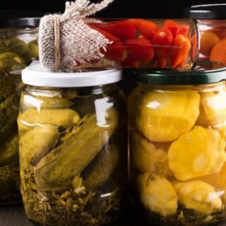 عبوات زجاجية شفافة تحتوي بداخلها على الخيار، البندورة، البطاطا والفليفلة