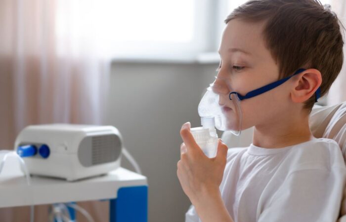 صبي صغير يضع قناع أكسجين على وجهه وينظر للأسفل